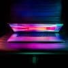Picture of a laptop with a neon wallpaper sitting on a chair half open in the dark