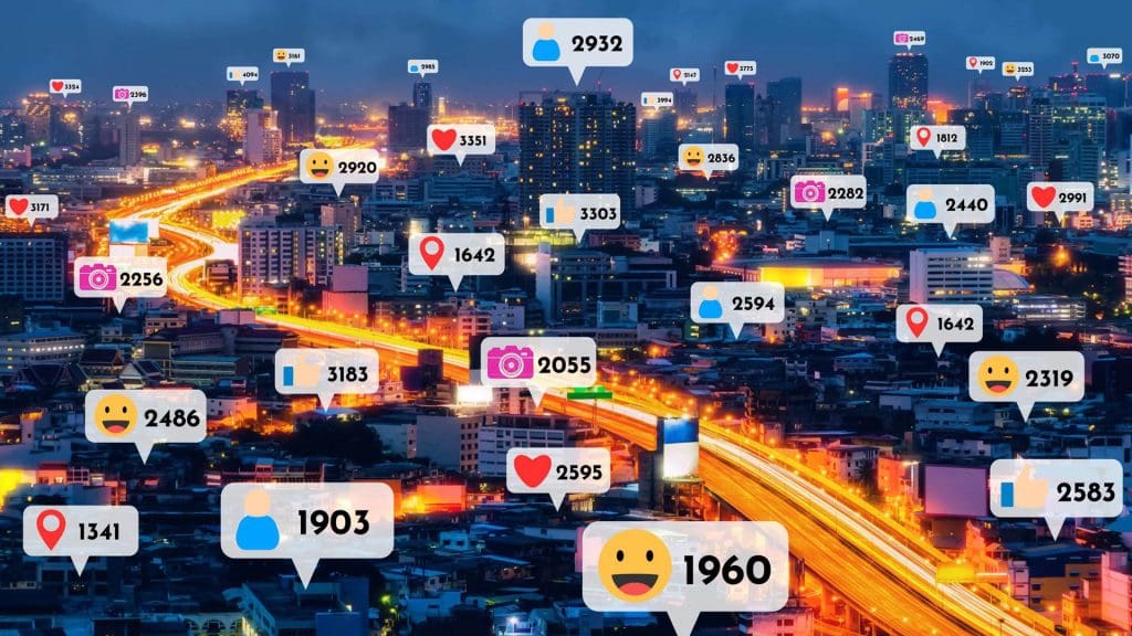 Photo of a city at night with chat bubbles with icons with a number representing interactions