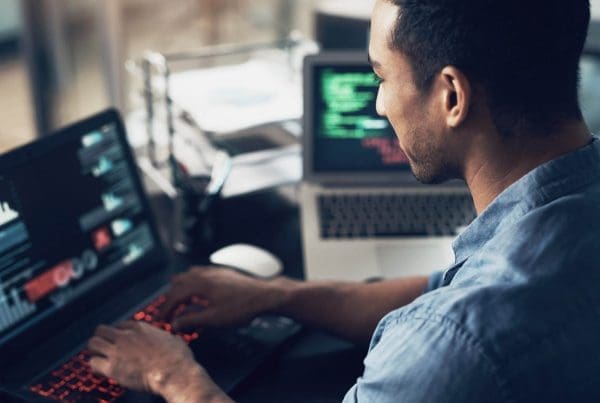Man typing on laptop while looking at analytics dashboard