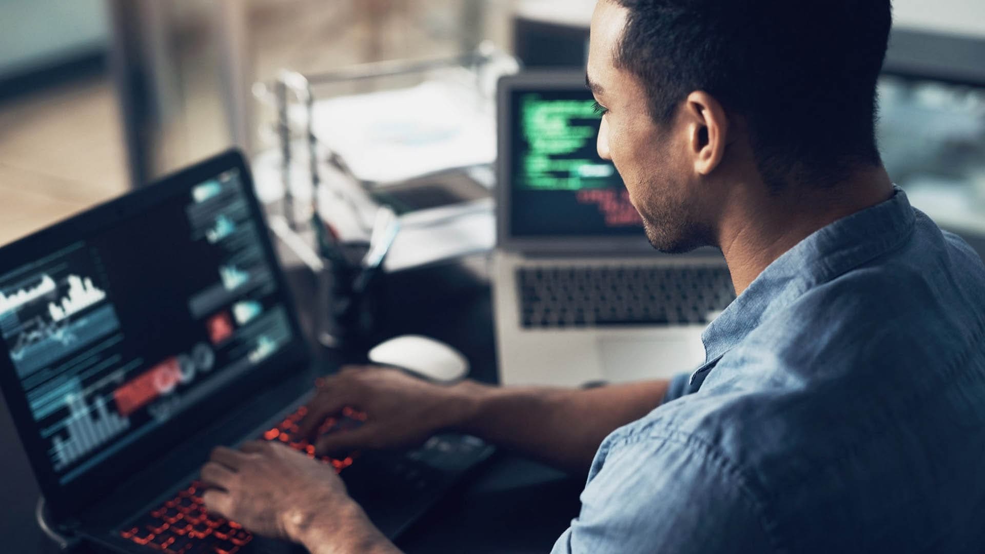 Man typing on laptop while looking at analytics dashboard